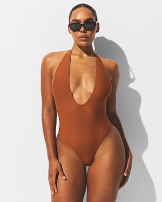 A MODEL POSES WEARING SKIMS ONE PIECE SWIMSUIT