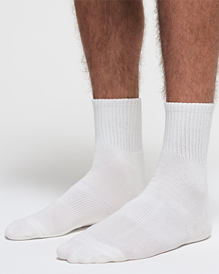 A MODEL POSES WEARING SKIMS MENS LOUNGE SOCKS