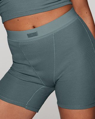 A MODEL POSES WEARING SKIMS BOXERS